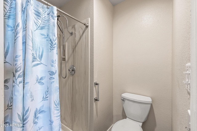 bathroom with a textured wall, a shower with curtain, and toilet