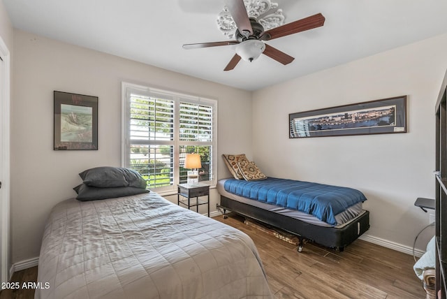 bedroom featuring ceiling fan, baseboards, and wood finished floors