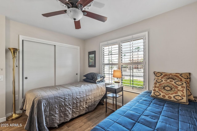 bedroom with wood finished floors, a closet, baseboards, and ceiling fan