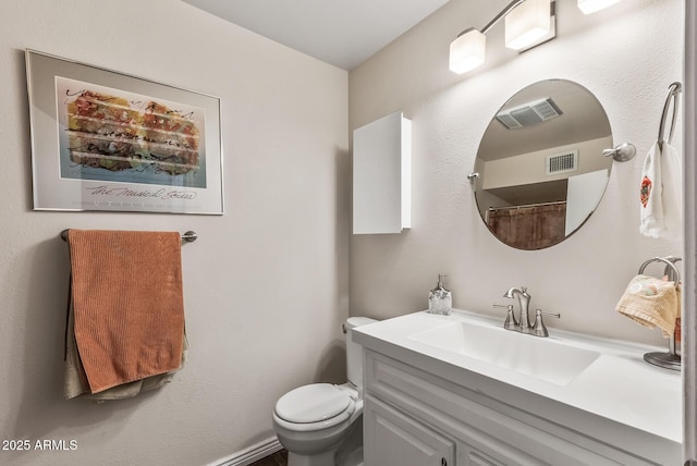 bathroom with toilet, vanity, and visible vents