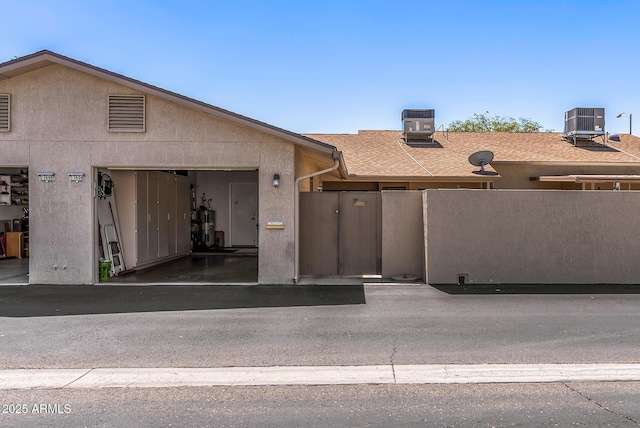 view of front of house featuring an attached garage, aphalt driveway, fence, and cooling unit