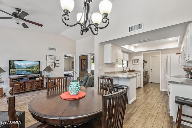 dining area featuring light wood-type flooring, visible vents, and ceiling fan with notable chandelier