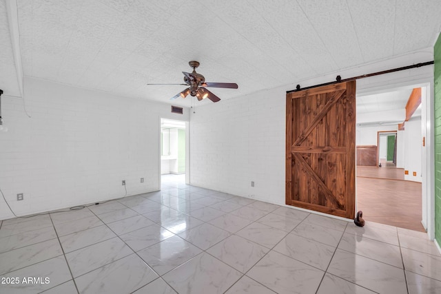 6217 W Orange Dr, Glendale, AZ 85301 - spare room featuring a ceiling fan, a barn door, and brick wall
