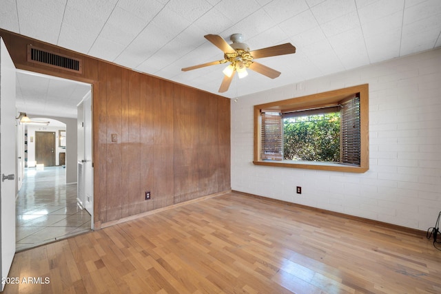 6217 W Orange Dr, Glendale, AZ 85301 - spare room featuring a ceiling fan, wood finished floors, wood walls, and brick wall