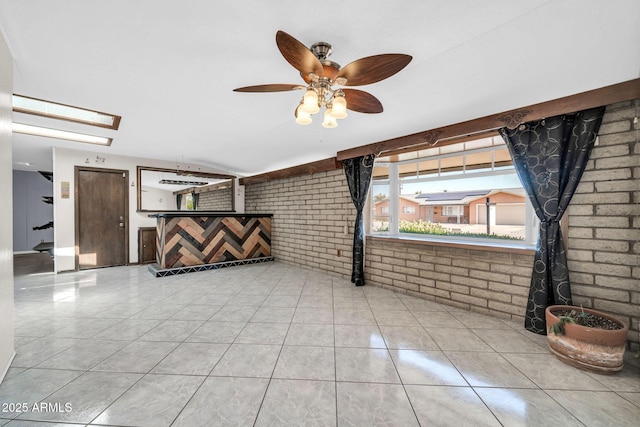 6217 W Orange Dr, Glendale, AZ 85301 - unfurnished living room with brick wall, a ceiling fan, and tile patterned floors