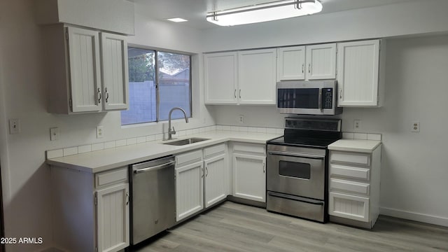 kitchen featuring light wood-type flooring, stainless steel appliances, white cabinetry, and sink