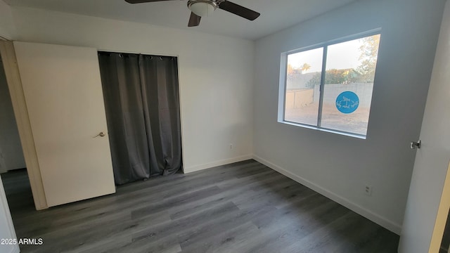 unfurnished bedroom featuring ceiling fan, multiple windows, wood-type flooring, and a closet