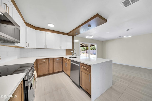 8146 N 17th Dr, Phoenix, AZ 85021 - kitchen with stainless steel appliances, a peninsula, a sink, light countertops, and backsplash