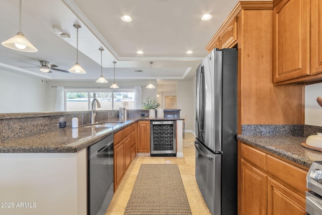 kitchen with pendant lighting, ceiling fan, appliances with stainless steel finishes, a tray ceiling, and beverage cooler