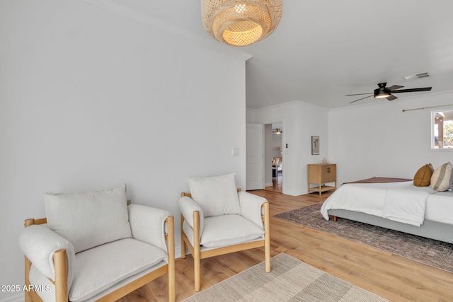 bedroom featuring light hardwood / wood-style floors, ceiling fan, and crown molding