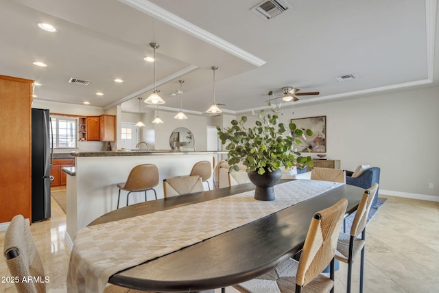 dining room with a raised ceiling, crown molding, and ceiling fan