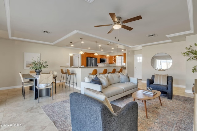 living room featuring a tray ceiling, ceiling fan, and crown molding