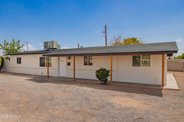 single story home featuring central air condition unit, roof with shingles, and fence