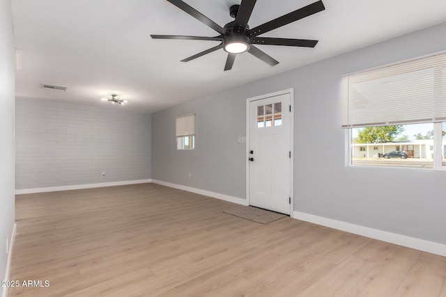 foyer with visible vents, baseboards, light wood-style flooring, and brick wall