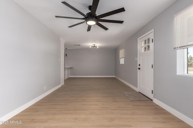 interior space with visible vents, brick wall, ceiling fan, baseboards, and light wood-style floors