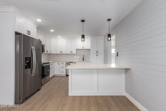 kitchen with a peninsula, light countertops, light wood-type flooring, and stainless steel appliances
