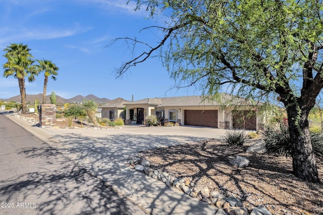 single story home featuring a mountain view, an attached garage, curved driveway, and stucco siding