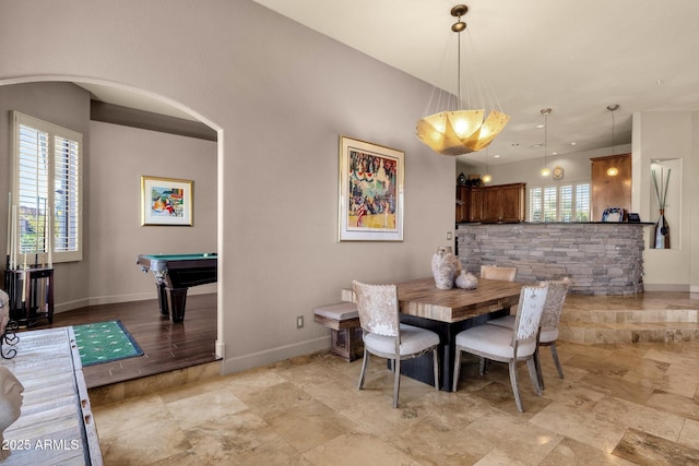 dining area featuring arched walkways, billiards, and baseboards