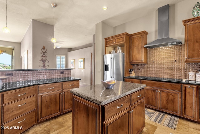 kitchen with wall chimney range hood, stainless steel refrigerator with ice dispenser, plenty of natural light, and backsplash