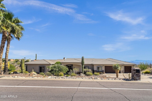 single story home featuring driveway, a tile roof, a mountain view, an attached garage, and stucco siding