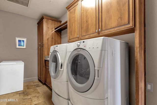 laundry room with stone finish floor, washing machine and dryer, visible vents, baseboards, and cabinet space