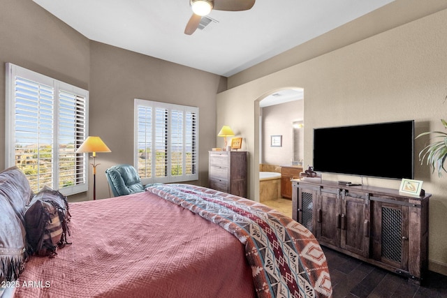 bedroom featuring arched walkways, wood finished floors, connected bathroom, visible vents, and a ceiling fan
