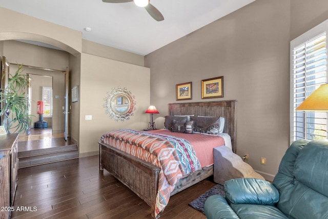 bedroom featuring wood finished floors, a ceiling fan, arched walkways, and baseboards