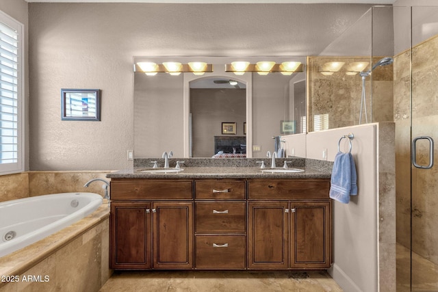 ensuite bathroom with a stall shower, double vanity, a tub with jets, and a sink