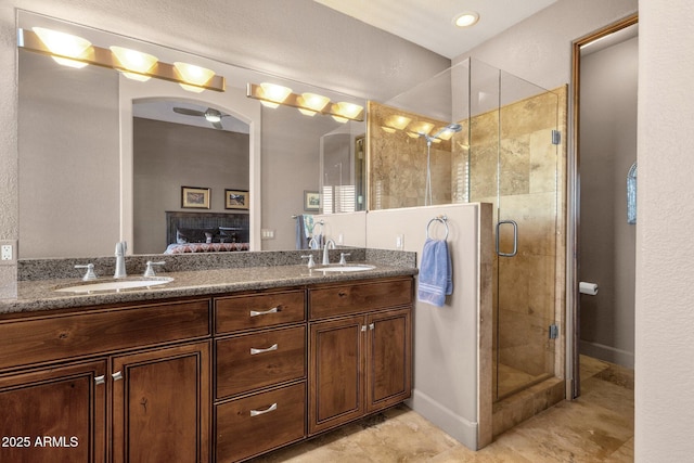ensuite bathroom featuring double vanity, connected bathroom, a stall shower, and a sink