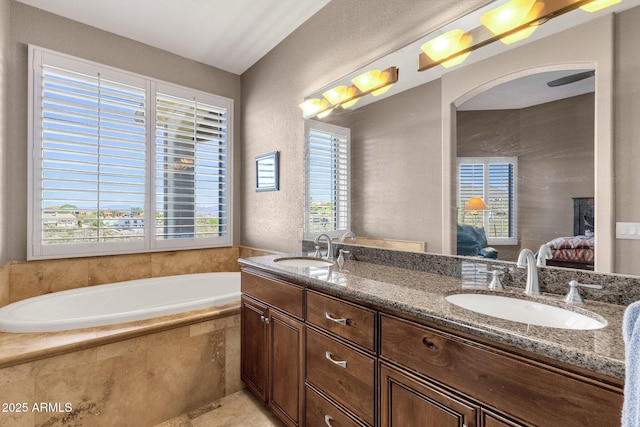 bathroom with a bath, connected bathroom, a textured wall, and a sink