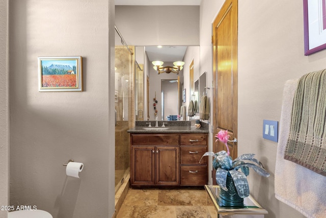 full bathroom with toilet, a stall shower, vanity, and stone finish flooring