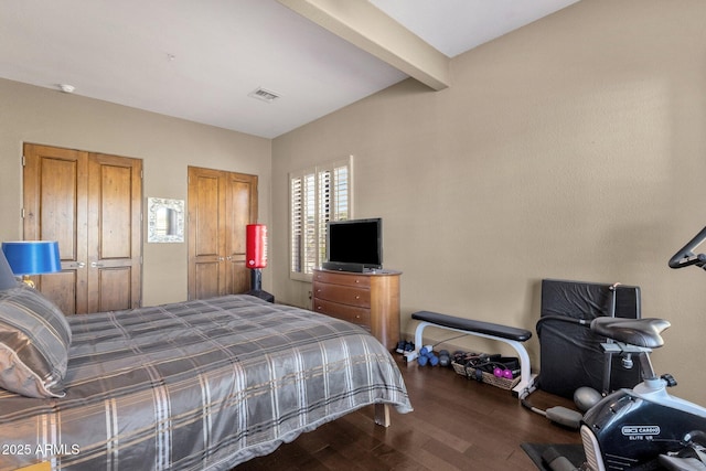 bedroom with beam ceiling, wood finished floors, and visible vents