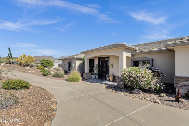 property entrance with a tile roof, stone siding, and stucco siding