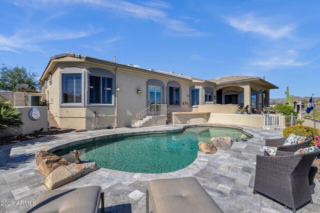 rear view of property with stucco siding, fence, a fenced in pool, central air condition unit, and a patio