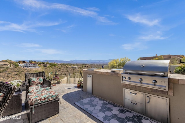 view of patio featuring exterior kitchen, a grill, and a mountain view