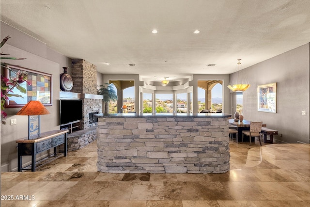 bar featuring recessed lighting, decorative light fixtures, stone finish floor, and a fireplace