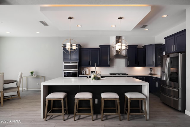 22421 N 34th St, Phoenix, AZ 85050 - kitchen featuring tasteful backsplash, a breakfast bar, a notable chandelier, appliances with stainless steel finishes, and wall chimney exhaust hood