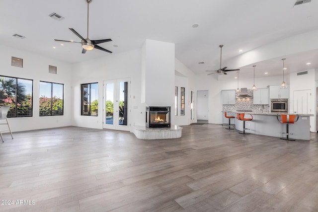 unfurnished living room with ceiling fan, a towering ceiling, and wood-type flooring