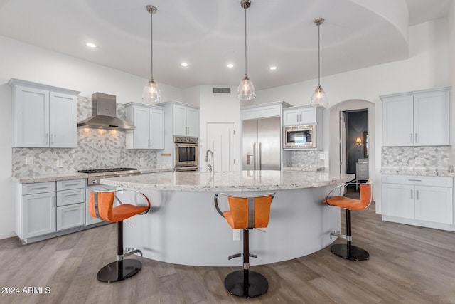 kitchen with tasteful backsplash, wall chimney exhaust hood, and decorative light fixtures