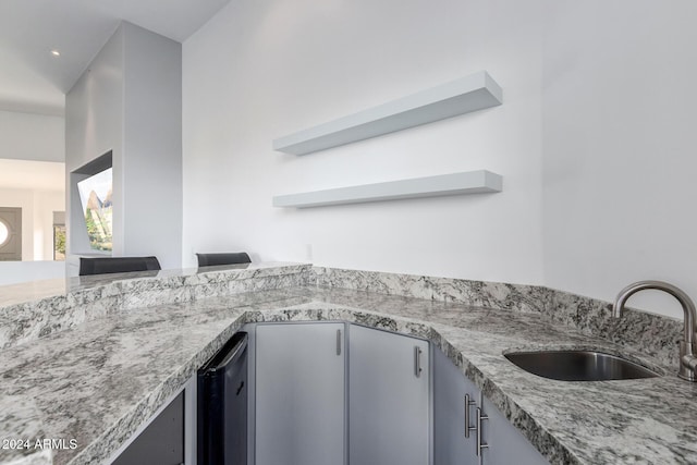 kitchen with light stone countertops, sink, and beverage cooler