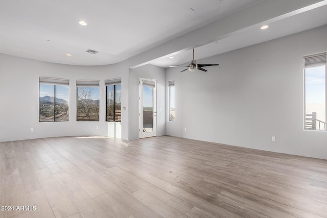 empty room with a wealth of natural light, ceiling fan, and light wood-type flooring