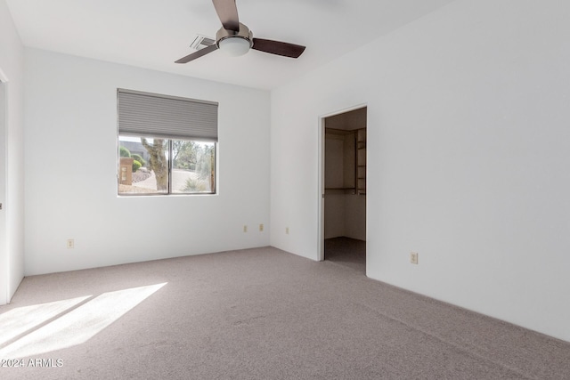 unfurnished bedroom featuring ceiling fan, light colored carpet, and a spacious closet