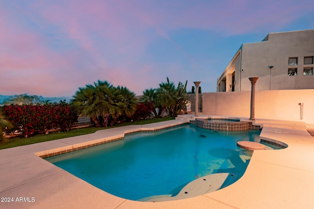 pool at dusk with an in ground hot tub