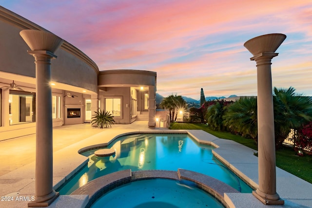 pool at dusk with a patio area and an in ground hot tub