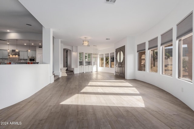 unfurnished living room with a notable chandelier and light hardwood / wood-style floors