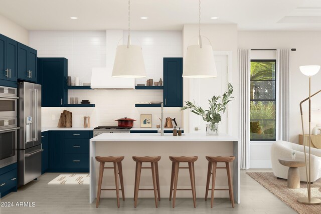 kitchen featuring stainless steel appliances, decorative backsplash, an island with sink, a kitchen bar, and light hardwood / wood-style flooring