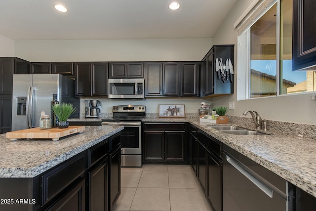 kitchen featuring stainless steel appliances, light stone countertops, sink, and light tile patterned floors