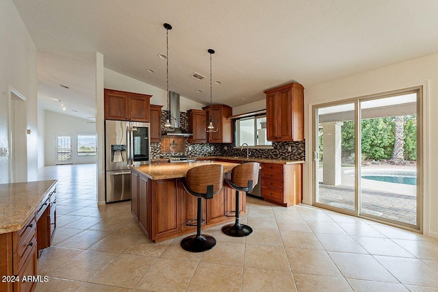 kitchen featuring wall chimney exhaust hood, stainless steel appliances, vaulted ceiling, and light stone counters