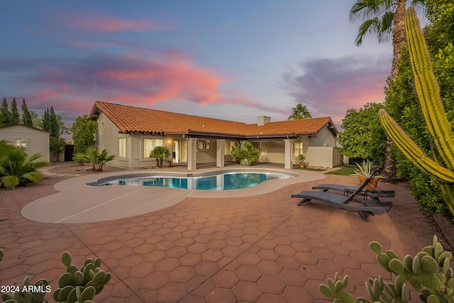 pool at dusk featuring a patio area