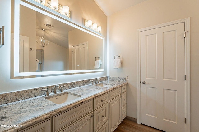 bathroom with lofted ceiling, hardwood / wood-style floors, vanity, and a notable chandelier